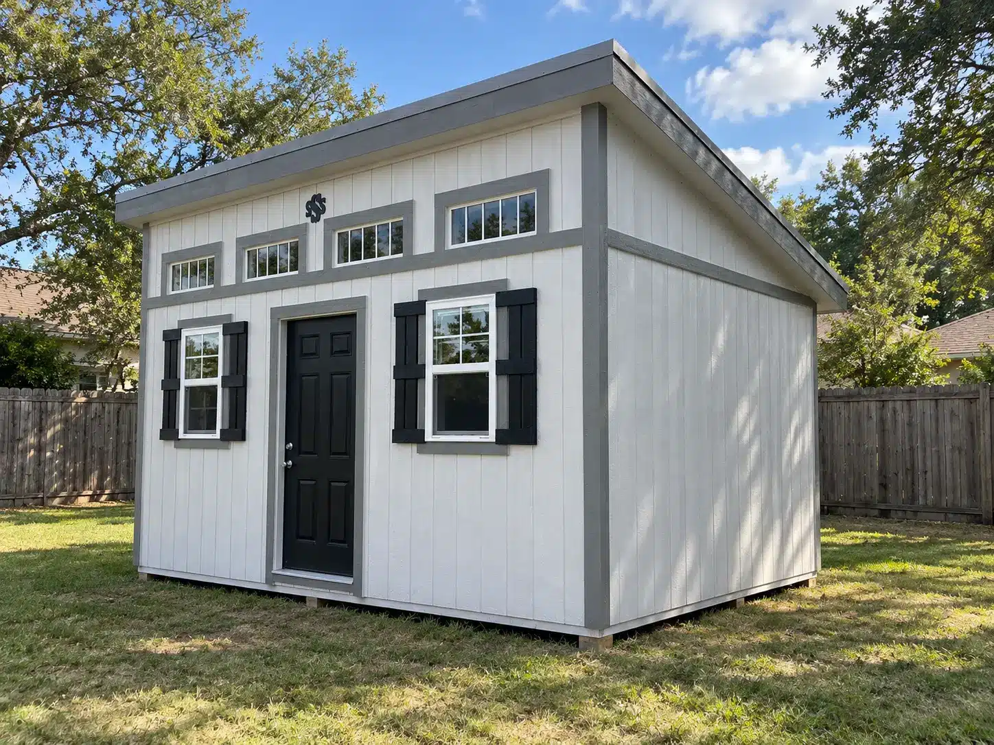 White studio building with gray trim, a black entry door and transom windows