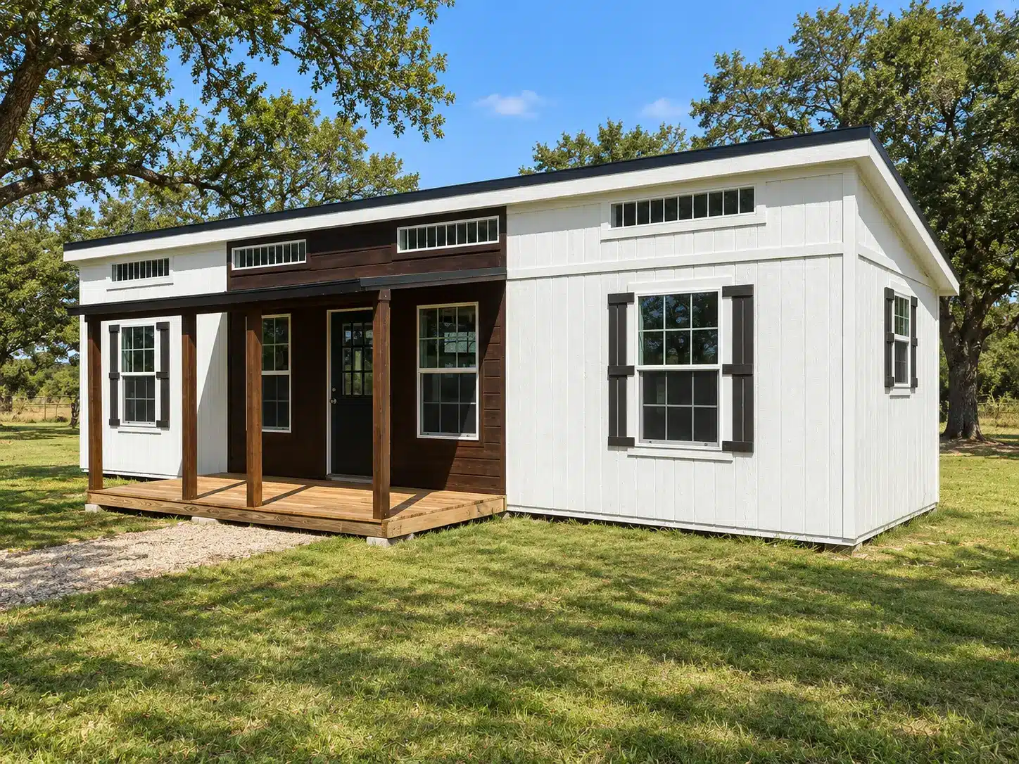 White tiny-home shell with dark trim and a wood porch